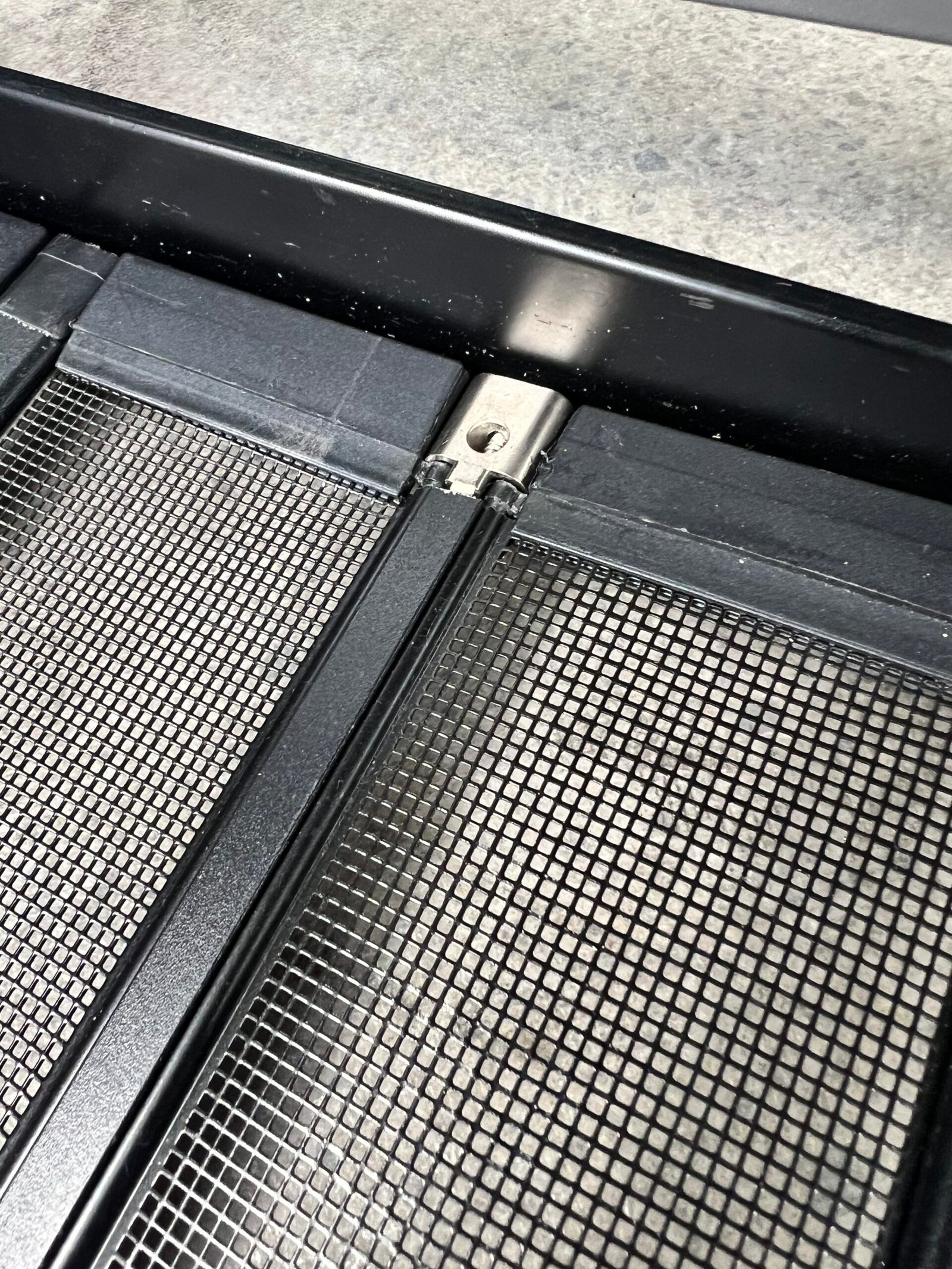 Close-up of the stainless steel hinge connecting two pet screen panels