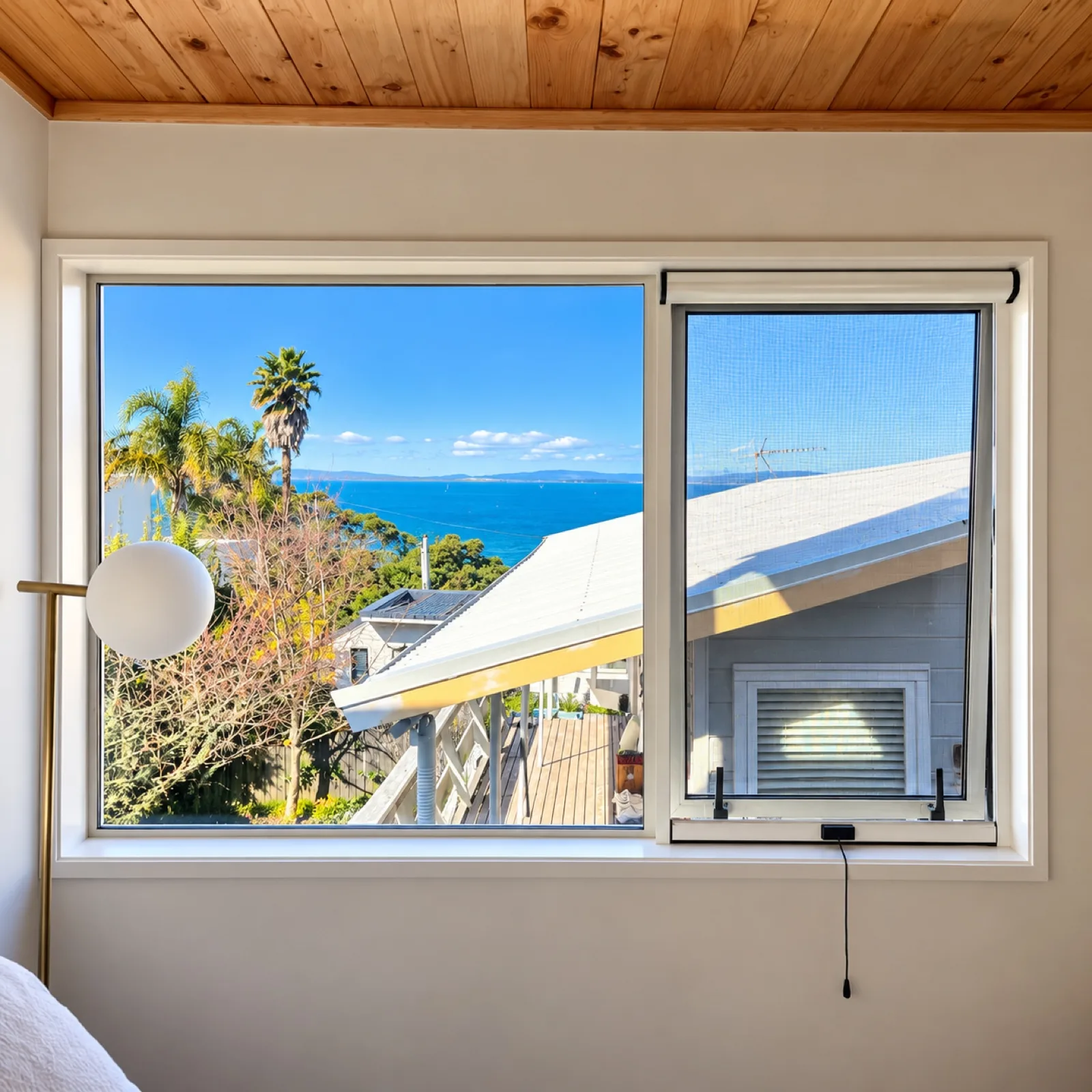 Retractable fly screen on a window with a coastal view